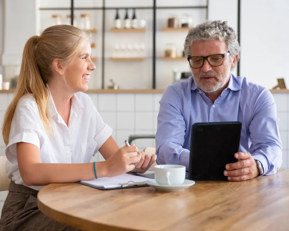 Consultora de pensiones IMSS explica a una pareja mayor cómo optimizar su edad de retiro con base actuarial.